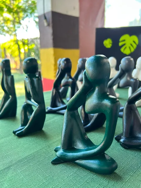 Esculturas pensadoras em verde-escuro enfileiradas na bancada da feira