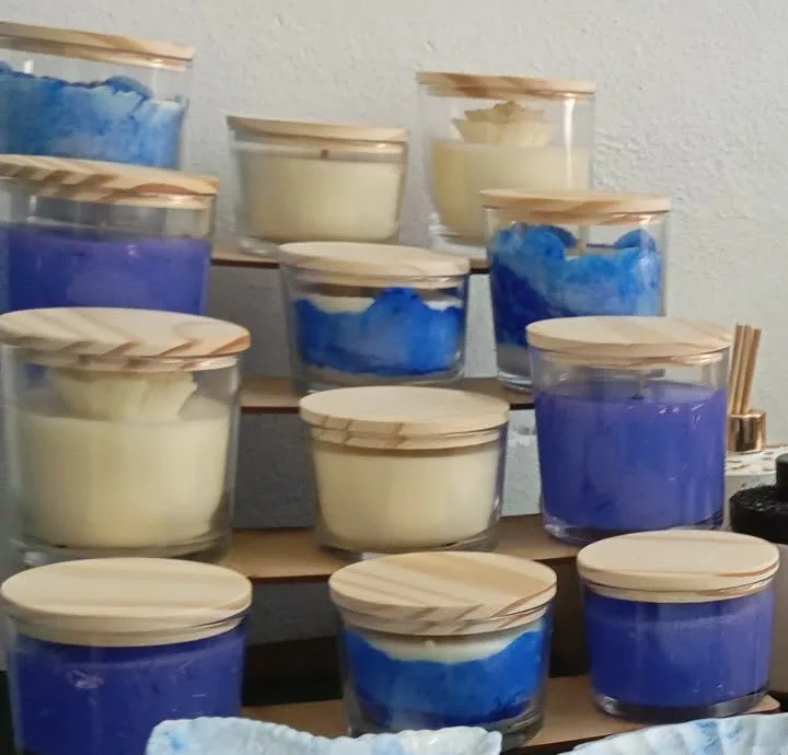 Velas em potes de vidro com tampas de madeira, em azul e branco, dispostas em degraus